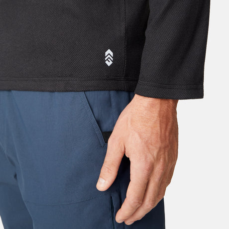 [Model is wearing size M.] Close-up of a person wearing a black long-sleeve shirt with a logo and blue pants on a white background.