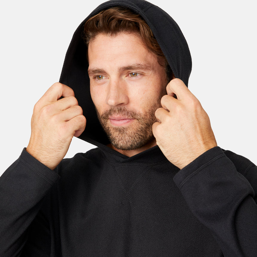 [Model is wearing size M.] Man wearing a black hoodie against a white background