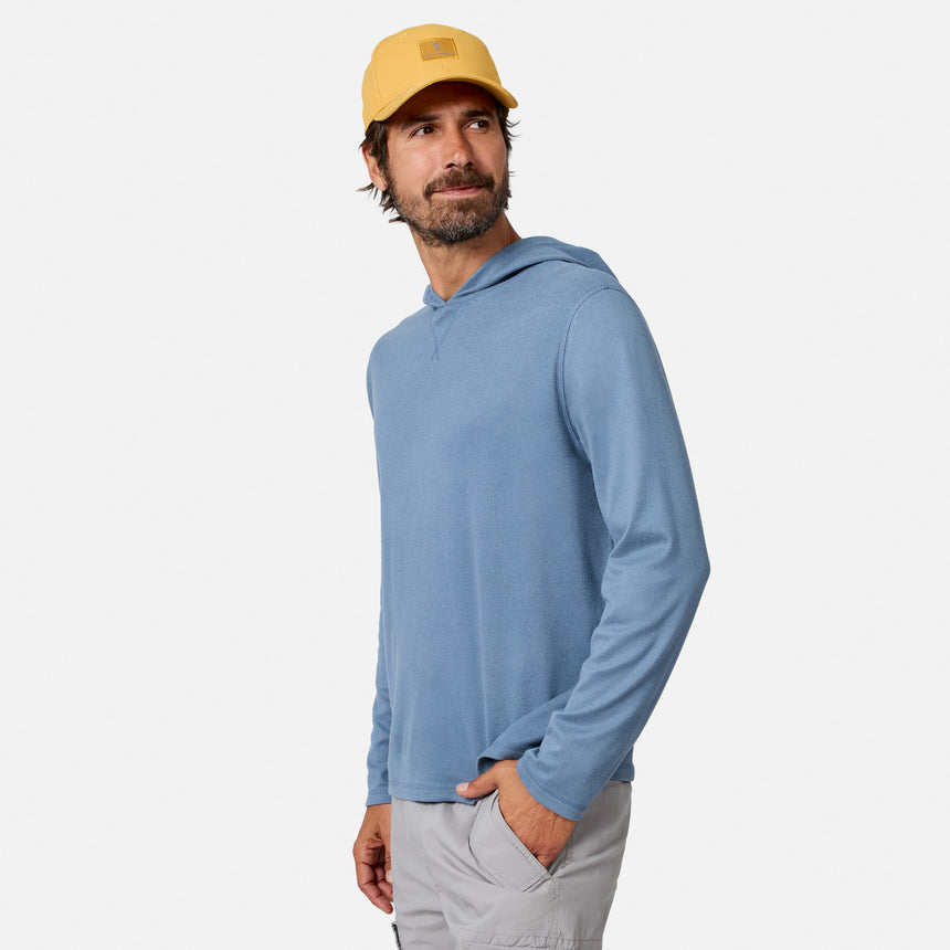 [Model is wearing size M.] A man wearing a light blue long-sleeve hooded shirt, a yellow baseball cap, and light gray pants, standing against a plain light gray studio background.