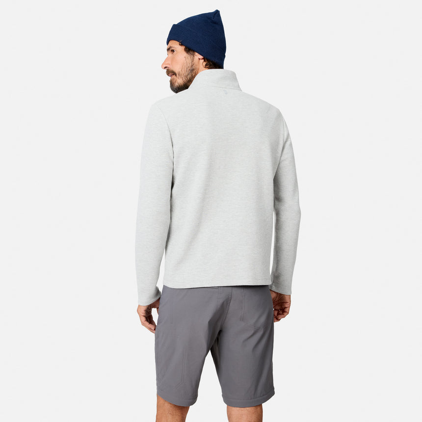 A man stands facing away against a plain white background, wearing a light gray Men’s Twill Interlock 1/4 Zip Long Sleeve Shirt by Free Country, paired with dark gray shorts and a navy beanie.