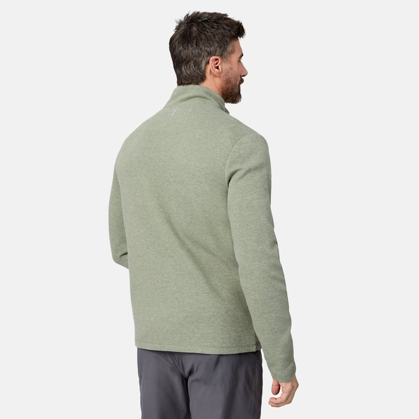 A man with short dark hair, standing and facing away from the camera against a plain white background, is wearing gray pants and a light green Men’s Twill Interlock 1/4 Zip Long Sleeve Shirt by Free Country.