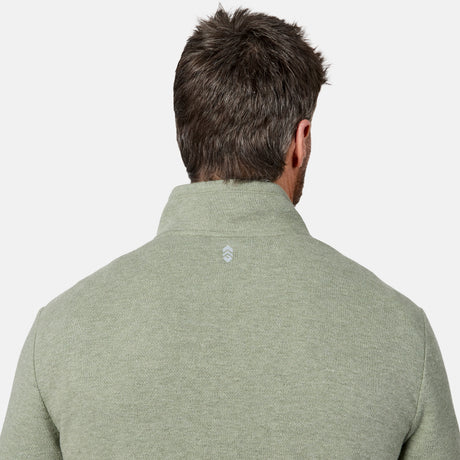 A man with short brown hair is shown from behind, wearing the Free Country Men’s Twill Interlock 1/4 Zip Long Sleeve Shirt in light olive green, featuring a breathable knit fabric and a small white logo on the upper back.