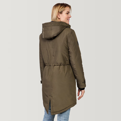 A woman smiles over her shoulder, wearing the Clearance Women's Arctic Anorak Jacket in olive green with eco-friendly REPREVE fill and light blue jeans, standing against a plain, light background.