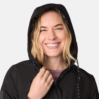[CJ is 5'10" wearing size S.] Women’s black hooded rain jacket with front zipper and snap button closure, flap pockets, and adjustable waist drawstring—styled with blue jeans for a casual, weather-ready look.