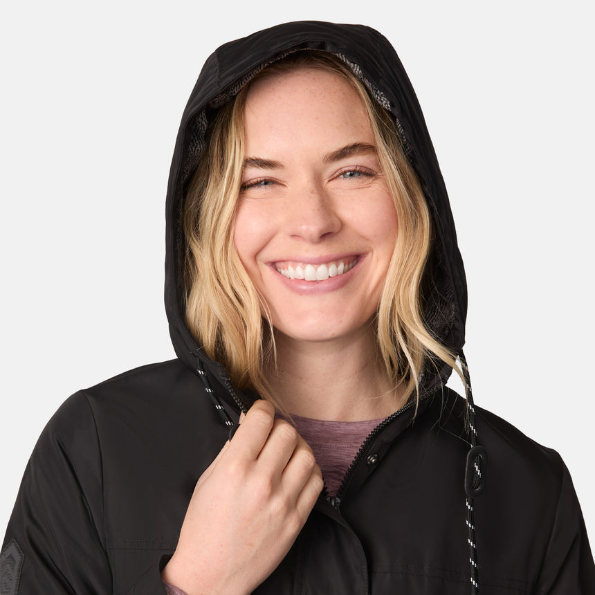 [CJ is 5'10" wearing size S.] Women’s black hooded rain jacket with front zipper and snap button closure, flap pockets, and adjustable waist drawstring—styled with blue jeans for a casual, weather-ready look.