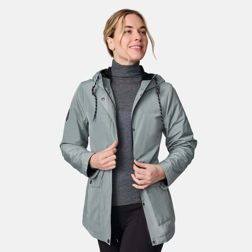 [CJ is 5'10" wearing size S.] Women’s light green hooded rain jacket with front zip closure, flap pockets with button accents, black hood drawstrings, and a sleeve patch—layered over a dark gray turtleneck and styled with black pants for a sleek, weather-ready look.