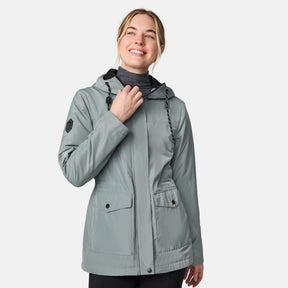 [CJ is 5'10" wearing size S.] Women’s light green hooded rain jacket with front zip closure, flap pockets with button accents, black hood drawstrings, and a sleeve patch—layered over a dark gray turtleneck and styled with black pants for a sleek, weather-ready look.