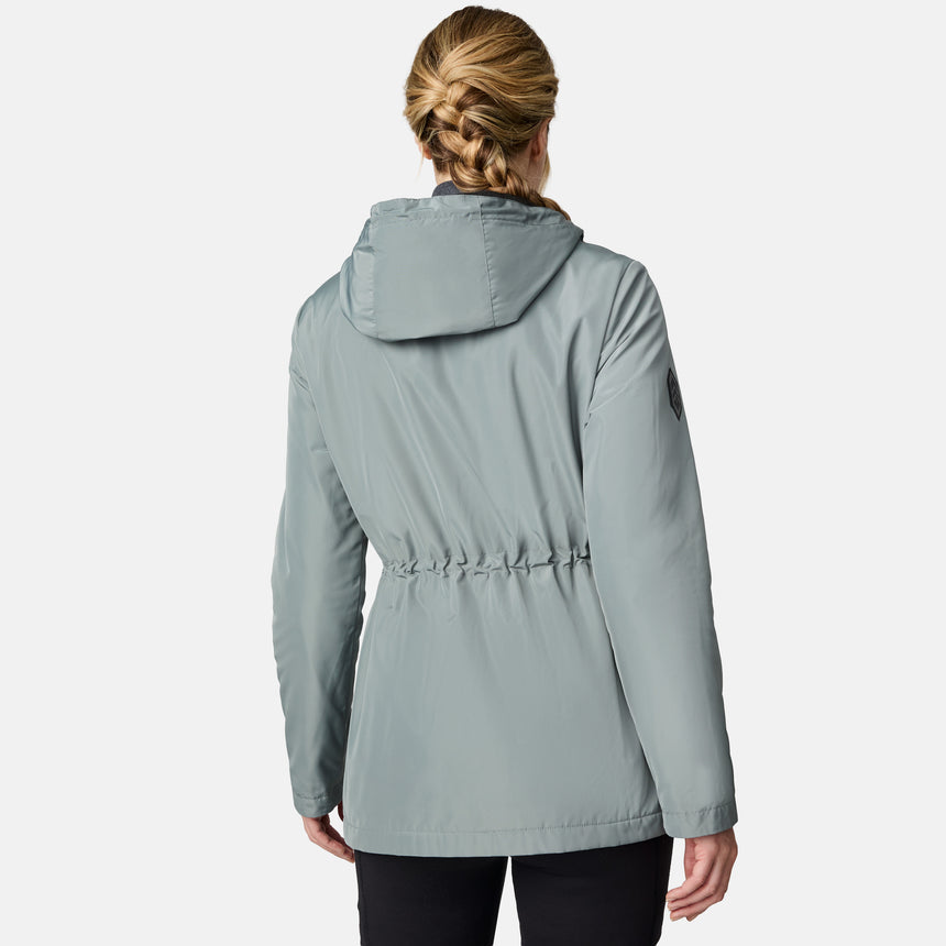 [CJ is 5'10" wearing size S.] Women’s light green hooded rain jacket with front zip closure, flap pockets with button accents, black hood drawstrings, and a sleeve patch—layered over a dark gray turtleneck and styled with black pants for a sleek, weather-ready look.