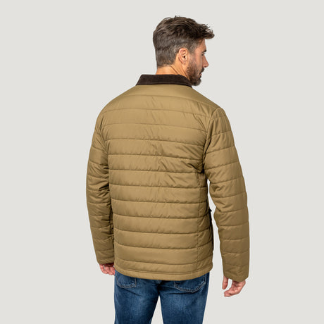 [Model is wearing size M.] A man viewed from the back wearing a tan quilted puffer jacket with a dark brown collar, paired with blue jeans, against a solid light gray background.