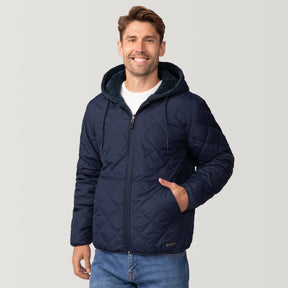 [Matt is 6'2" wearing a size Medium.] Men’s Free Country reversible quilted jacket in navy with zip-front closure, adjustable drawstring hood, and dual hand pockets—flips to plush sherpa interior for added warmth and comfort. Styled with a white crewneck shirt and jeans for a casual, cold-weather look.