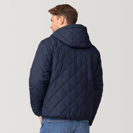 [Matt is 6'2" wearing a size Medium.] Men’s Free Country reversible quilted jacket in navy with zip-front closure, adjustable drawstring hood, and dual hand pockets—flips to plush sherpa interior for added warmth and comfort. Styled with a white crewneck shirt and jeans for a casual, cold-weather look.