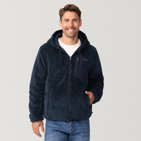 [Matt is 6'2" wearing a size Medium.] Men’s Free Country reversible quilted jacket in navy with zip-front closure, adjustable drawstring hood, and dual hand pockets—flips to plush sherpa interior for added warmth and comfort. Styled with a white crewneck shirt and jeans for a casual, cold-weather look.