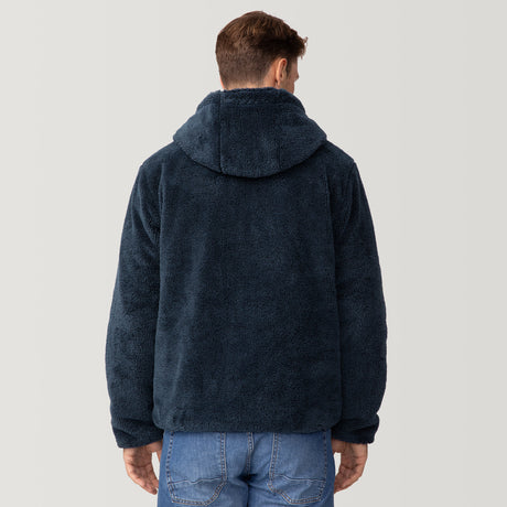 [Matt is 6'2" wearing a size Medium.] Men’s Free Country reversible quilted jacket in navy with zip-front closure, adjustable drawstring hood, and dual hand pockets—flips to plush sherpa interior for added warmth and comfort. Styled with a white crewneck shirt and jeans for a casual, cold-weather look.
