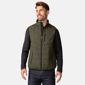 [Matt is 6'2" wearing a size Medium.] Man wearing the Free Country Men's FreeCycle® Stimson Puffer Vest in green, featuring quilted design, REPREVE® poly fill, and a vertical zip, layered over a black long-sleeve shirt with dark jeans.