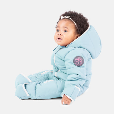 A baby in the Clearance Kids' Out of Bound Puffer Snow Suit, featuring light blue sherpa lining, a sleeve patch, and double zippers, sits on a white background looking slightly upward and to the side.