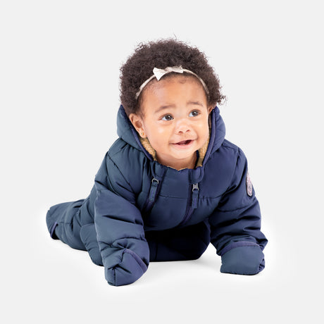 A baby wears the Clearance Kids' Out of Bound Puffer Snow Suit in navy blue with sherpa lining and double zippers, paired with a white headband, crawling on a white background with a gentle, curious look.