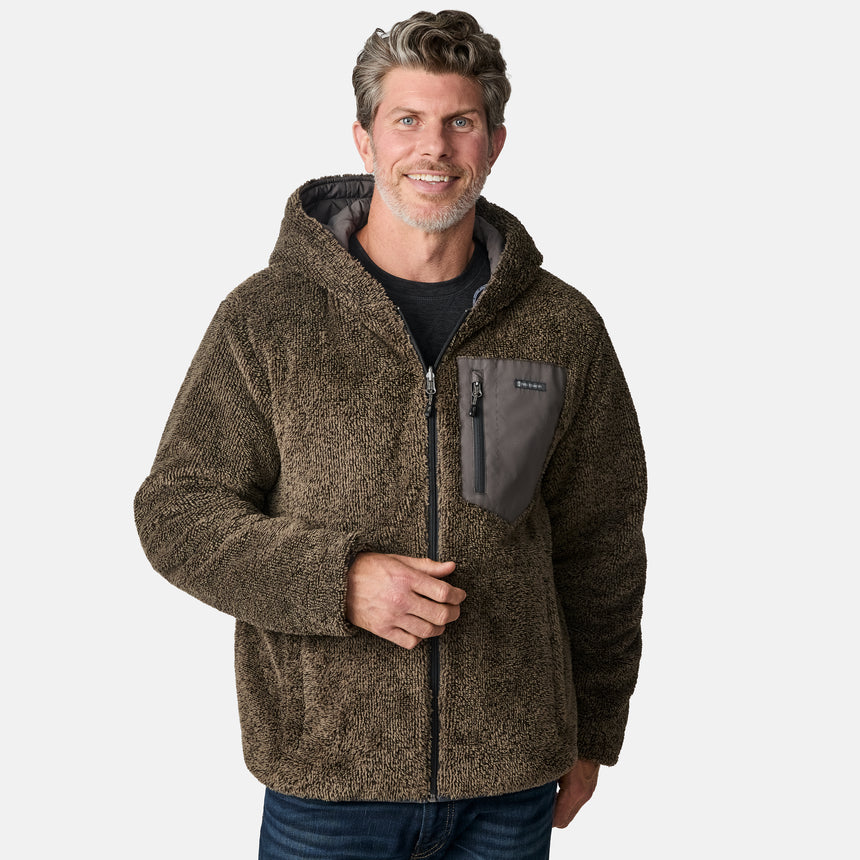 [Kolby is 6'2" wearing size M.] Men’s Free Country grey quilted hooded jacket with full-zip closure, adjustable drawstring hood, and dual hand pockets—reversible to a plush sherpa lining for enhanced warmth and cozy comfort. Styled over a dark crewneck and jeans for an effortlessly rugged, cold-weather vibe.