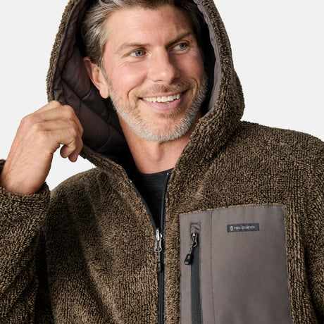 [Kolby is 6'2" wearing size M.] Men’s Free Country grey quilted hooded jacket with full-zip closure, adjustable drawstring hood, and dual hand pockets—reversible to a plush sherpa lining for enhanced warmth and cozy comfort. Styled over a dark crewneck and jeans for an effortlessly rugged, cold-weather vibe.