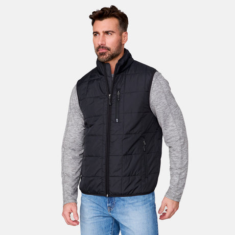 [Justin is 6'1" wearing size M.] Men’s Free Country black quilted vest with zip-front closure and stand collar—layered over a gray long-sleeve shirt and blue jeans. Designed for lightweight warmth and styled for transitional weather versatility.