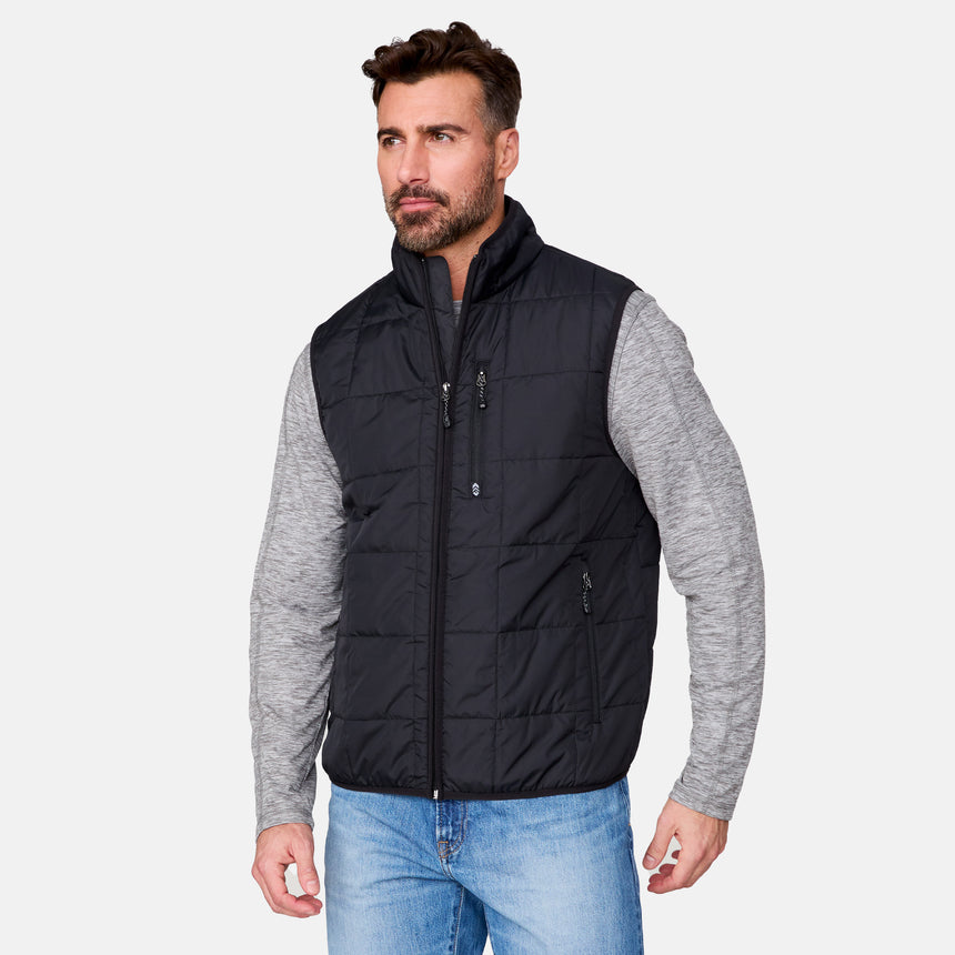 [Justin is 6'1" wearing size M.] Men’s Free Country black quilted vest with zip-front closure and stand collar—layered over a gray long-sleeve shirt and blue jeans. Designed for lightweight warmth and styled for transitional weather versatility.