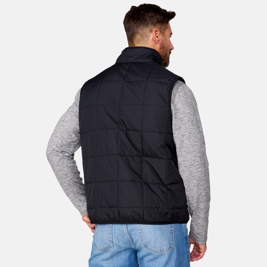 [Justin is 6'1" wearing size M.] Men’s Free Country black quilted vest with zip-front closure and stand collar—layered over a gray long-sleeve shirt and blue jeans. Designed for lightweight warmth and styled for transitional weather versatility.