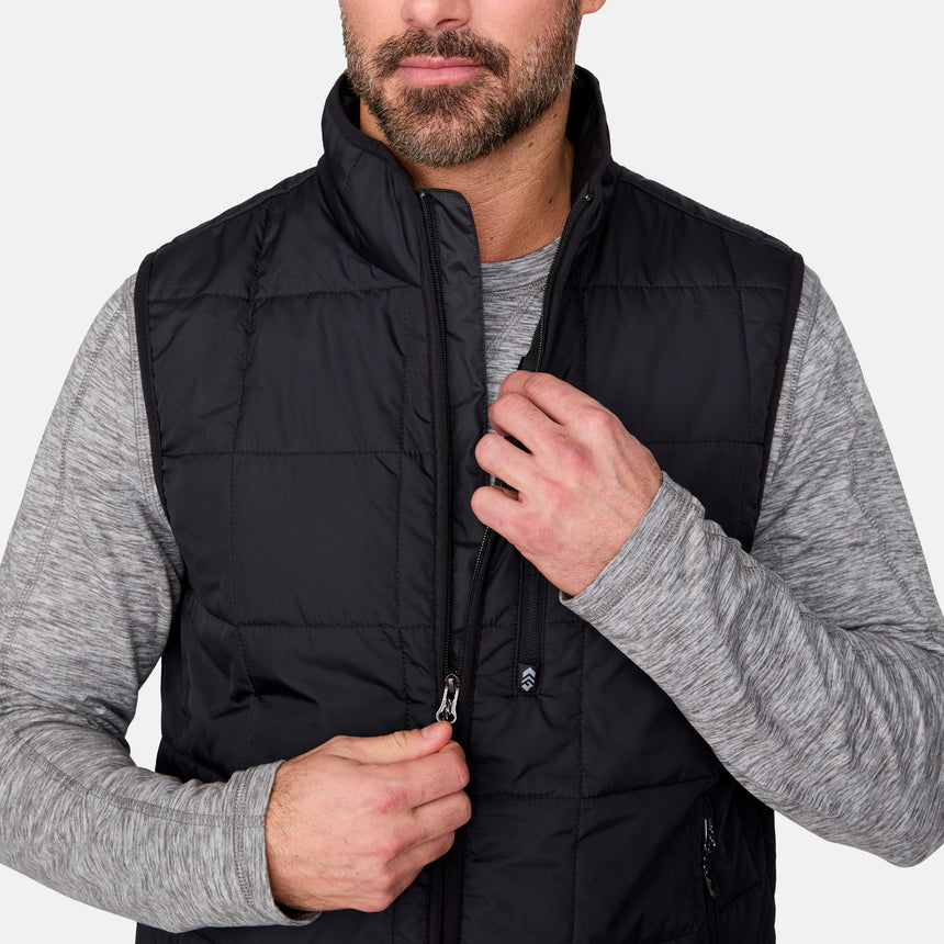 [Justin is 6'1" wearing size M.] Men’s Free Country black quilted vest with zip-front closure and stand collar—layered over a gray long-sleeve shirt and blue jeans. Designed for lightweight warmth and styled for transitional weather versatility.