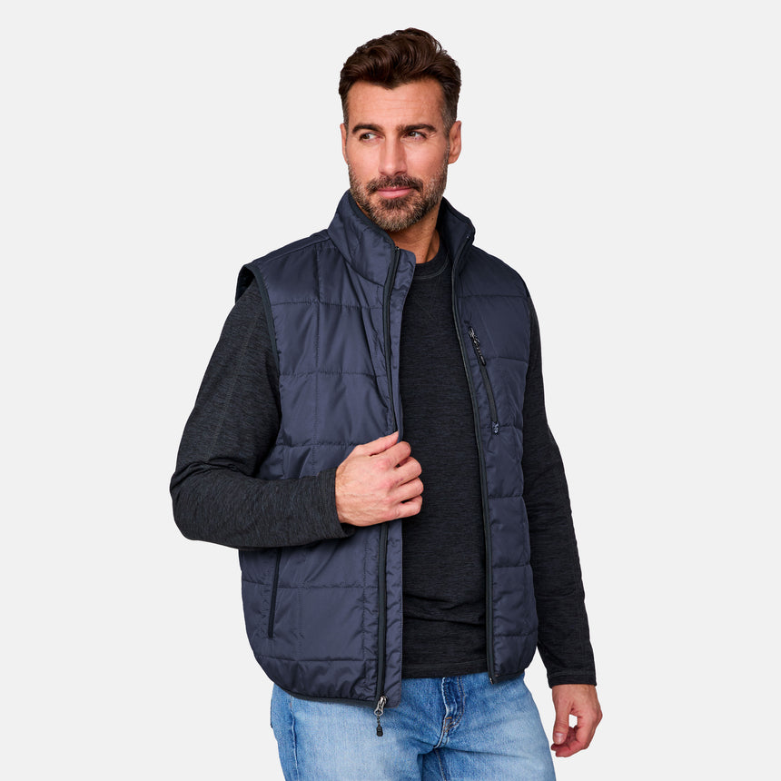 [Justin is 6'1" wearing size M.] Man wearing a navy puffer vest over a black shirt on a light gray background