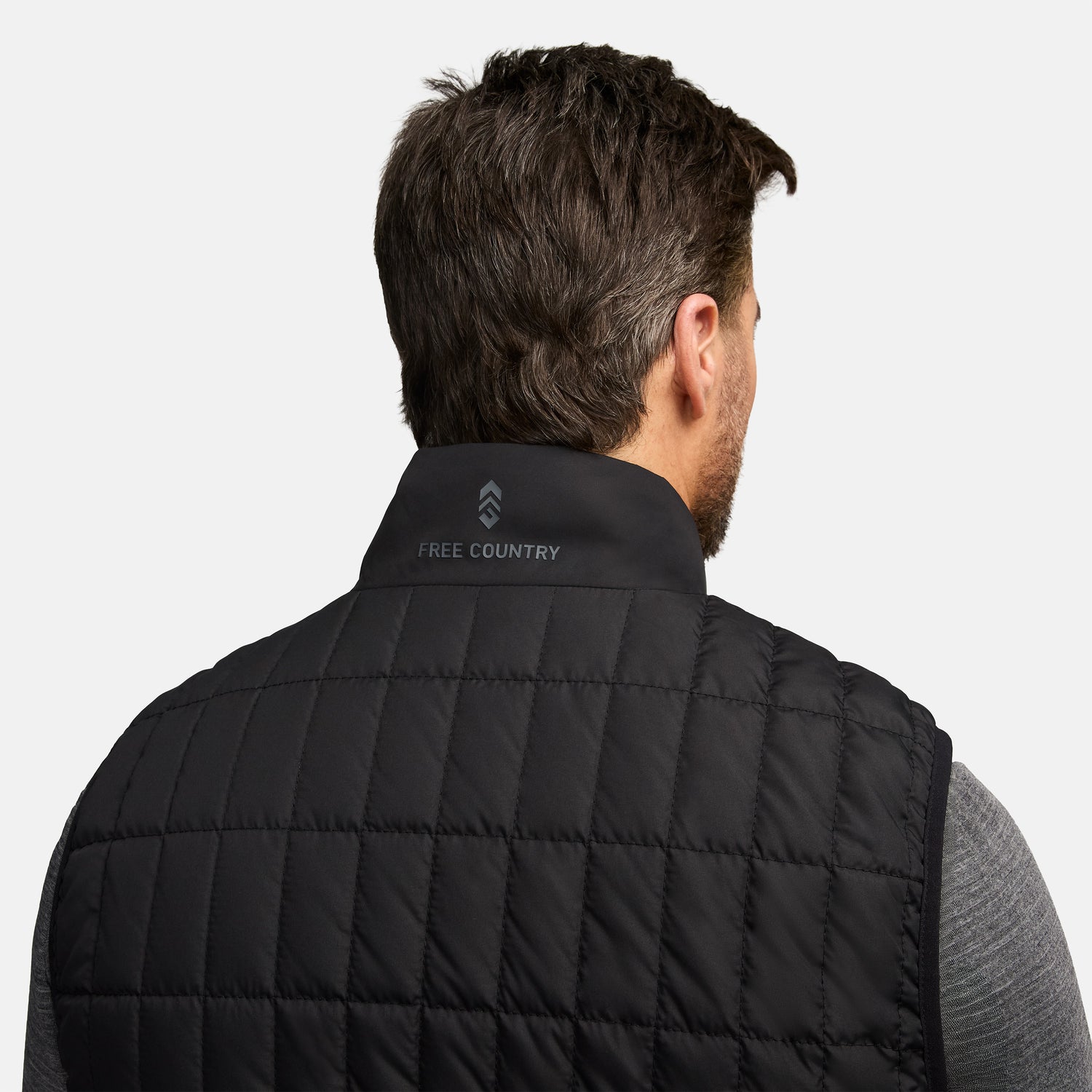 Back of the black quilted puffer vest with a neck logo and Free Country branding on the collar