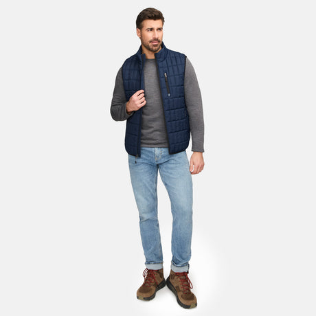 Male model wearing blue Sperrin full zip puffer vest over a gray long sleeve shirt
