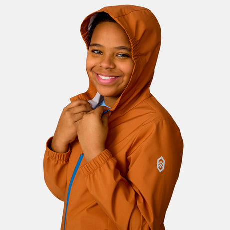 [Model is wearing a size Medium.] Boy wearing the Free Country Boys' Hydro Lite Recess X2O Rain Jacket in Autumn, size M, featuring lightweight wind resistant and waterproof fabric and an attached hood, paired with blue jeans #color_ autumn