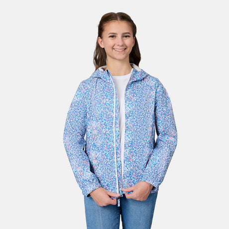 A smiling young person models the Free Country Girls' Recess X2O Rain Jacket in blue and white over a white shirt and blue jeans, standing against a plain white background.