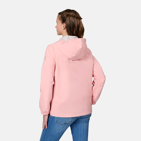 A woman with light brown braided hair is seen from behind, wearing a Free Country Girls' Recess X2O Rain Jacket in light pink and blue jeans against a plain, light background.