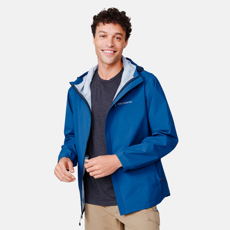 [Miguel is 6'2" wearing a size Medium.] Man wearing Free Country Men's Hydro Lite X2O Spectator Waterproof Jacket in Denim, size M, made from lightweight four way stretch performance fabric featuring sealed seams, elastic cuffs, and an attached hood with a drawcord, styled with khaki pants #color_denim