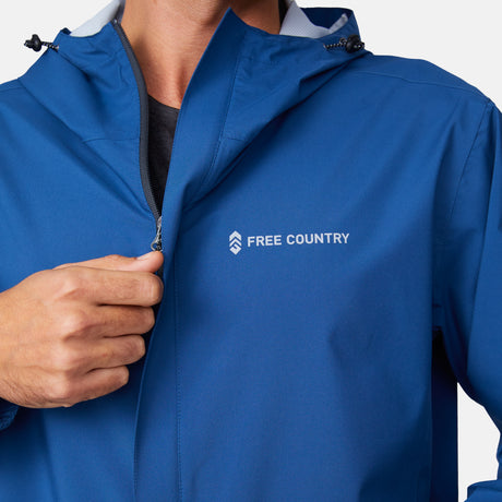 [Miguel is 6'2" wearing a size Medium.] Man wearing Free Country Men's Hydro Lite X2O Spectator Waterproof Jacket in Denim, size M, made from lightweight four way stretch performance fabric featuring sealed seams, elastic cuffs, and an attached hood with a drawcord, styled with khaki pants #color_denim