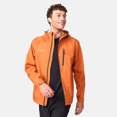 [Miguel is 6'2" wearing a size Medium.] Man wearing Free Country Men's Hydro Lite X2O Status Jacket in Autumn, size M, made from lightweight four way stretch water-resistant performance fabric featuring tab cuffs, an attached hood with a drawcord, and a chest and lower pockets, styled with black pants #color_autumn