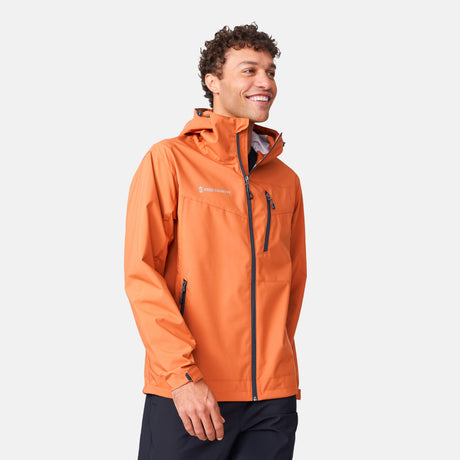 [Miguel is 6'2" wearing a size Medium.] Man wearing Free Country Men's Hydro Lite X2O Status Jacket in Autumn, size M, made from lightweight four way stretch water-resistant performance fabric featuring tab cuffs, an attached hood with a drawcord, and a chest and lower pockets, styled with black pants #color_autumn