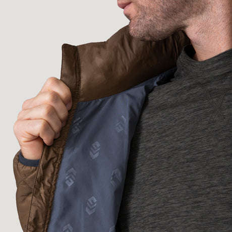 [Vince is 6'1" wearing a size Medium.] Man wearing the Free Country Men's Apex Quilted Puffer Jacket in brown, layered over a grey shirt and jeans, standing against a light background.