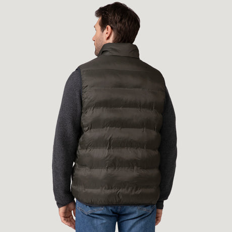 A man is seen from behind wearing the Clearance Men's Pine Creek Quilted Reversible Vest in dark gray over a textured gray long-sleeve shirt and blue jeans, set against a light gray background.
