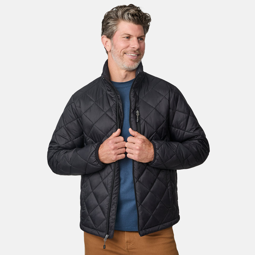 [Kolby is 6'2" wearing size M] Model wearing a black quilted Free Country jacket with diamond-pattern stitching, high stand collar, and zippered chest pocket; paired with brown pants and a blue crewneck tee for a warm, transitional-weather look.