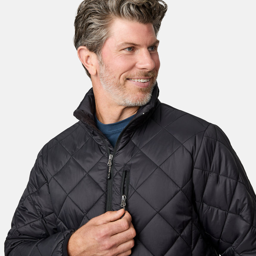 [Kolby is 6'2" wearing size M] Model wearing a black quilted Free Country jacket with diamond-pattern stitching, high stand collar, and zippered chest pocket; paired with brown pants and a blue crewneck tee for a warm, transitional-weather look.