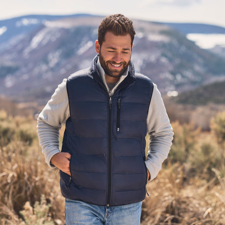 Man wearing a black puffer vest in a mountainous landscape