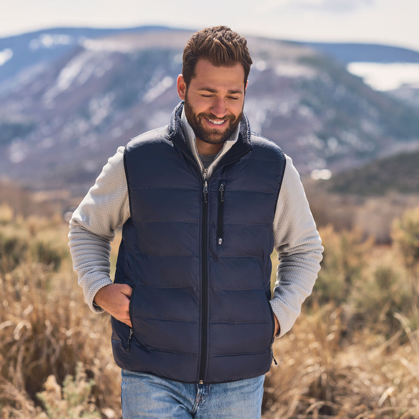 Man wearing a black puffer vest in a mountainous landscape