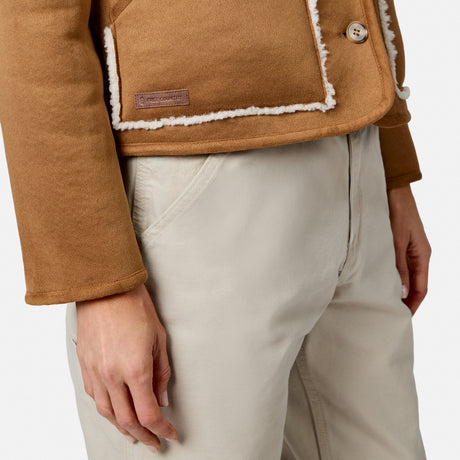 Close up of brown suede jacket with sherpa trim showing pocket edge and leather patch label