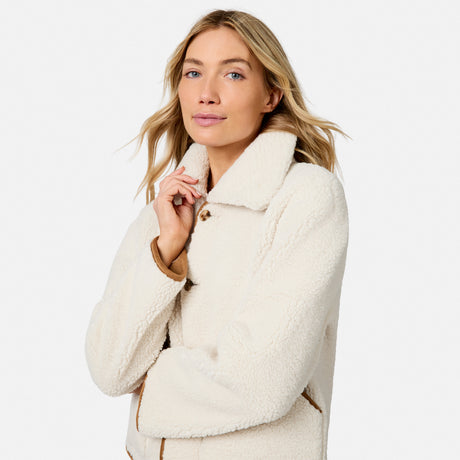 Woman wearing a cream faux suede shearling reversible jacket with a plush white collar