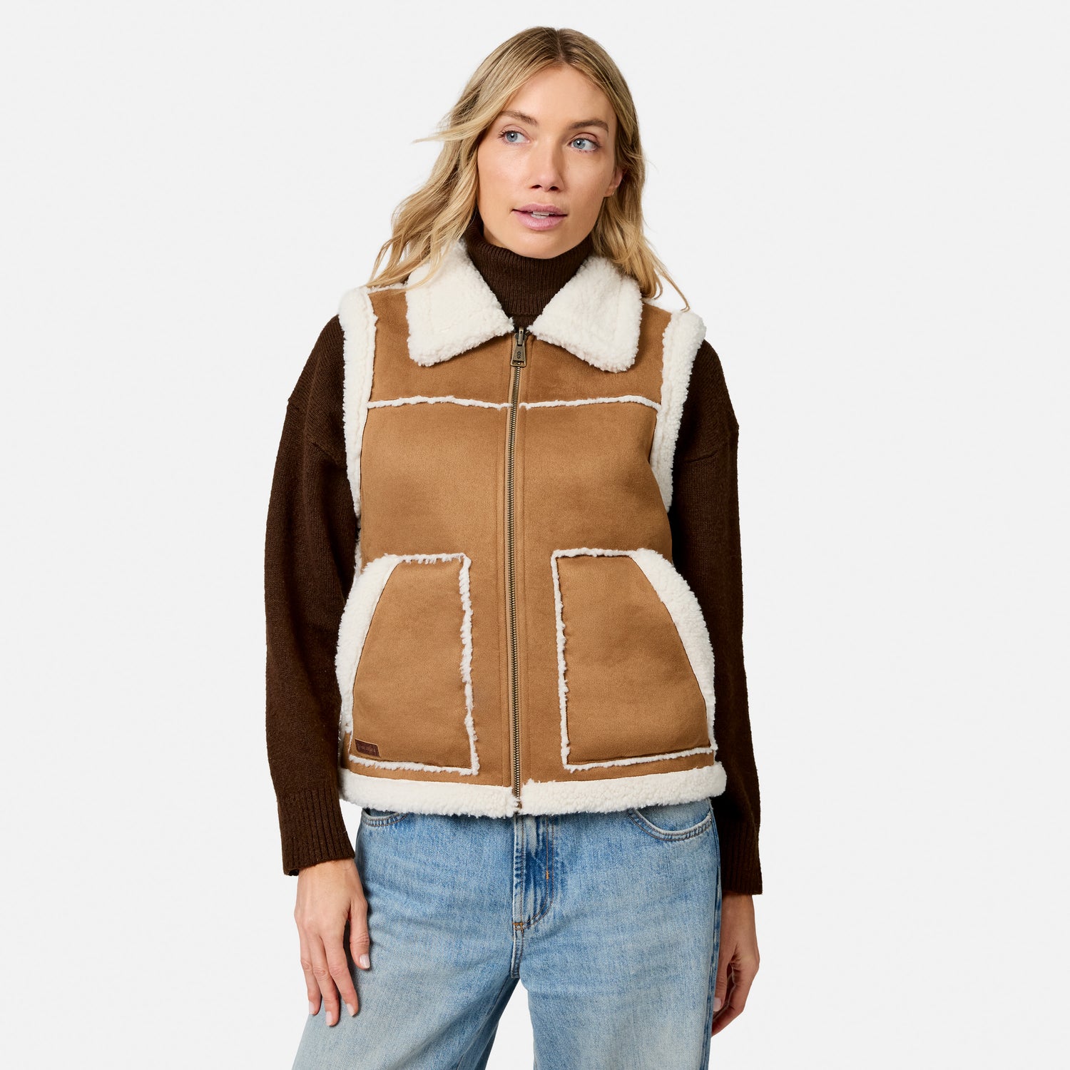 Model wearing brown faux suede shearling reversible vest over a dark brown turtleneck, front view