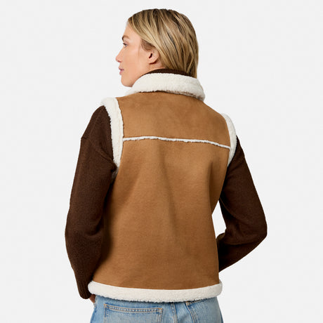 Side profile of a woman in a brown faux suede reversible vest with white shearling collar.
