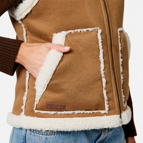 Close-up of brown faux suede shearling vest showing white fleece trim and front pocket