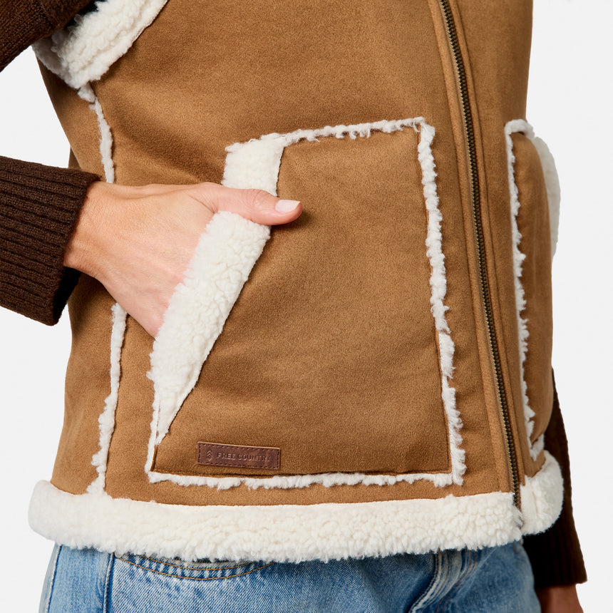 Close-up of brown faux suede shearling vest showing white fleece trim and front pocket