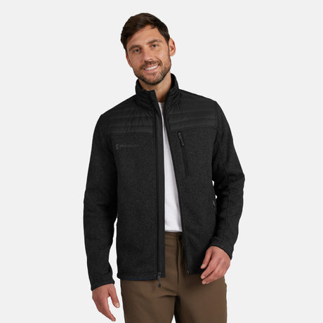 [Model is wearing size M.] Man wearing Free Country Men's Frore Knit Fleece Jacket in black with a full zip front, zipper chest pocket, light grey background. Perfect men’s jacket for fall weather.