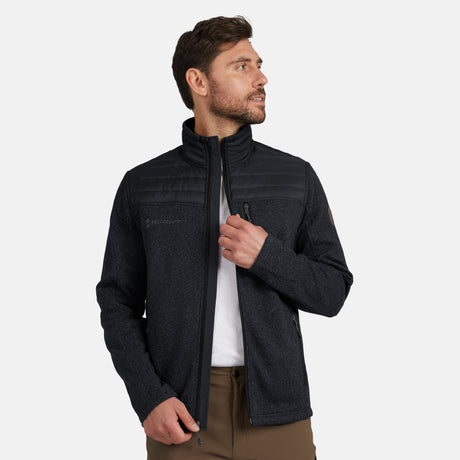 [Model is wearing size M.] Man wearing Free Country Men's Frore Knit Fleece Jacket in black with a full zip front, zipper chest pocket, light grey background. Perfect men’s jacket for fall weather.
